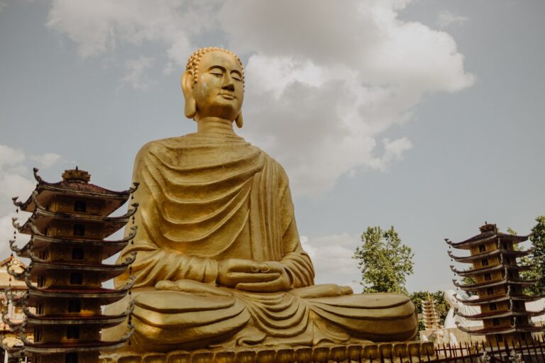 a statue of a buddha sitting in front of pagodas